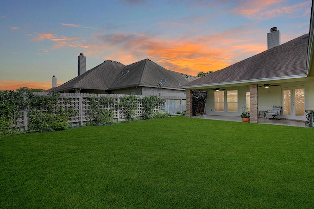 6613 Belvoir Ave, Corpus Christi, TX 78414 - back of house at dusk featuring french doors, a ceiling fan, a shingled roof, a chimney, and a patio