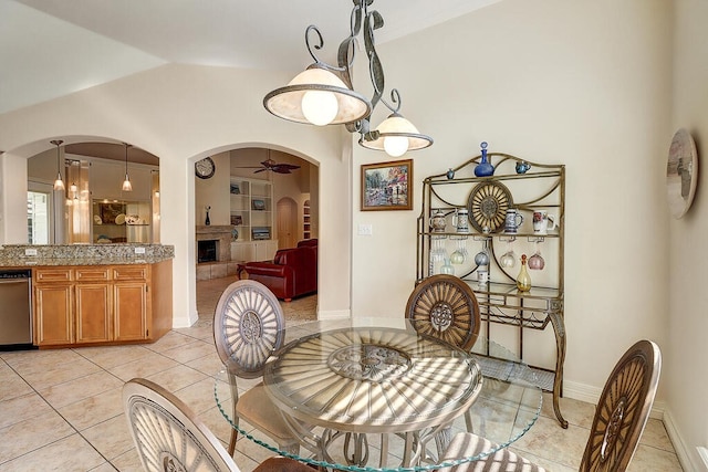 6613 Belvoir Ave, Corpus Christi, TX 78414 - dining area with arched walkways, ceiling fan, light tile patterned floors, vaulted ceiling, and a tile fireplace