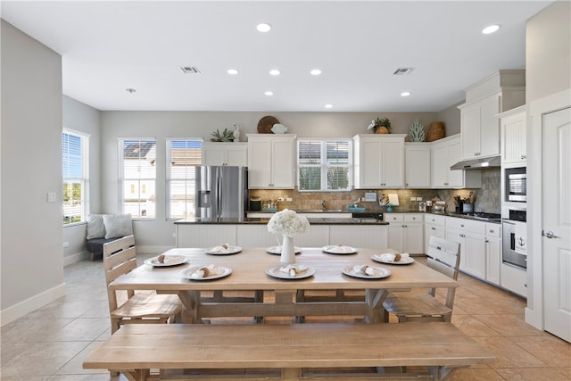 kitchen with stainless steel appliances, white cabinets, light tile patterned floors, and decorative backsplash