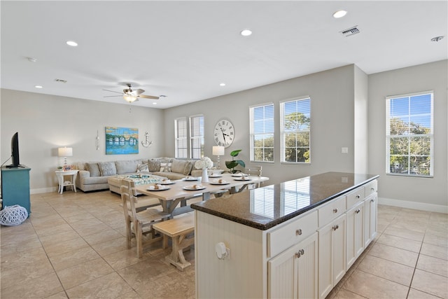 kitchen featuring white cabinets, a wealth of natural light, a kitchen island, and dark stone countertops