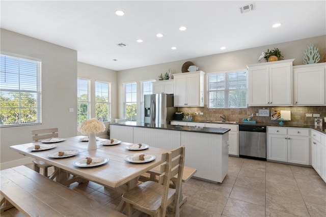 kitchen with a center island, appliances with stainless steel finishes, decorative backsplash, and white cabinets