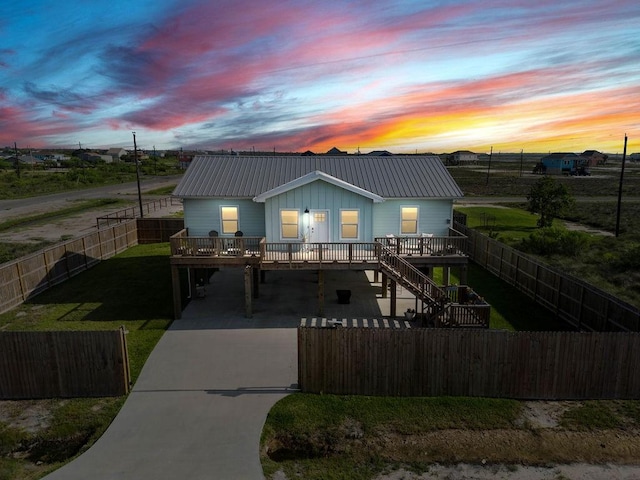 view of front facade with metal roof, concrete driveway, a fenced backyard, and a carport