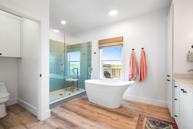 full bathroom with toilet, wood finished floors, a stall shower, baseboards, and vanity