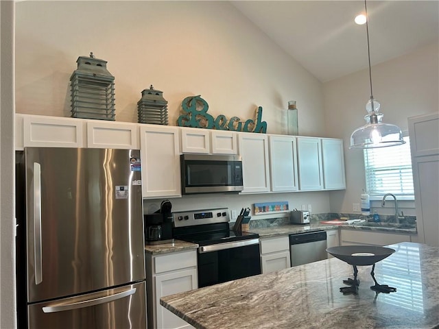 15110 Arashi Beach Dr, Corpus Christi, TX 78418 - kitchen featuring appliances with stainless steel finishes, vaulted ceiling, white cabinets, stone counters, and decorative light fixtures
