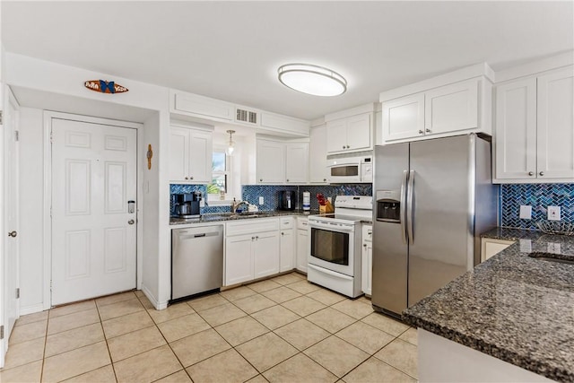 700 Island Retreat Rd Unit 138, Port Aransas, TX 78373 - kitchen with appliances with stainless steel finishes, backsplash, white cabinets, and light tile patterned floors