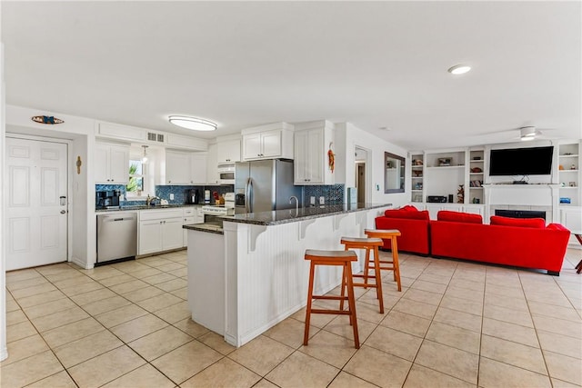 700 Island Retreat Rd Unit 138, Port Aransas, TX 78373 - kitchen featuring appliances with stainless steel finishes, a peninsula, light tile patterned floors, and a breakfast bar