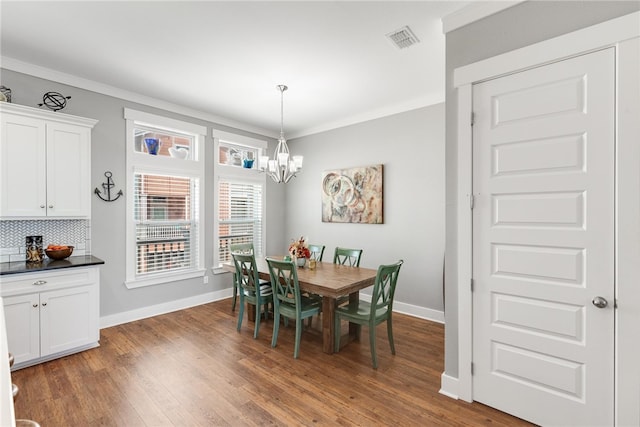 dining area with dark hardwood / wood-style flooring, a notable chandelier, and ornamental molding