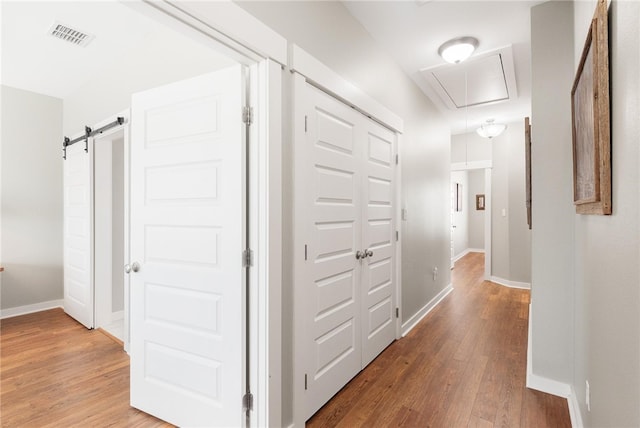 hallway with a barn door and hardwood / wood-style floors