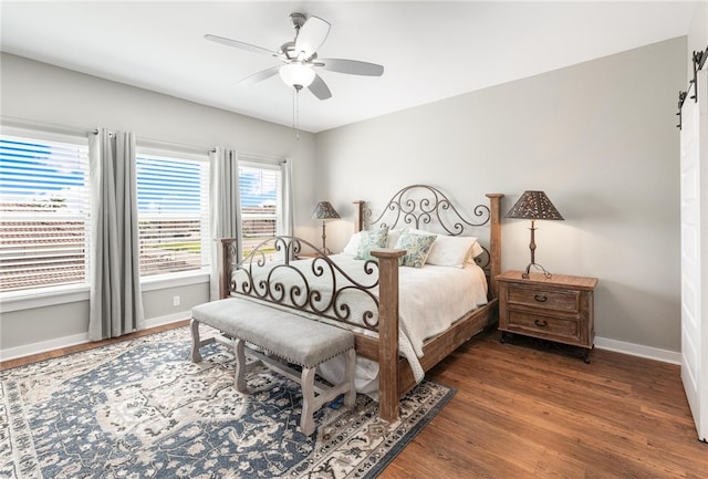 bedroom featuring dark hardwood / wood-style flooring, a barn door, and ceiling fan