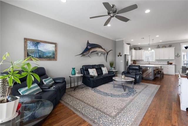 living room featuring ceiling fan, sink, dark hardwood / wood-style floors, and crown molding