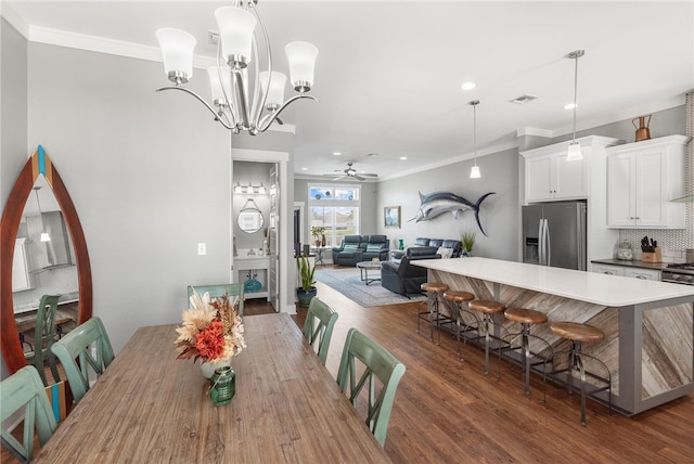 dining room featuring dark wood-type flooring, crown molding, and ceiling fan with notable chandelier