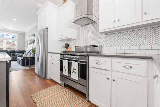 kitchen featuring stainless steel appliances, dark hardwood / wood-style flooring, white cabinets, crown molding, and wall chimney range hood