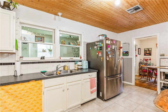 4009 Pope Dr, Corpus Christi, TX 78411 - kitchen featuring freestanding refrigerator, light tile patterned floors, wooden ceiling, decorative backsplash, and white cabinets