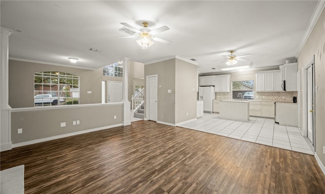 kitchen featuring white cabinetry, backsplash, decorative columns, white refrigerator with ice dispenser, and light wood-type flooring