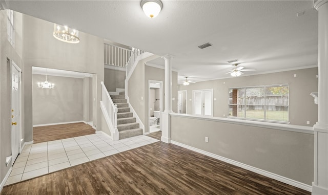 foyer with decorative columns, wood-type flooring, ceiling fan with notable chandelier, and crown molding