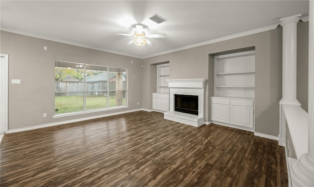 unfurnished living room featuring dark wood-type flooring, a brick fireplace, built in features, ceiling fan, and decorative columns