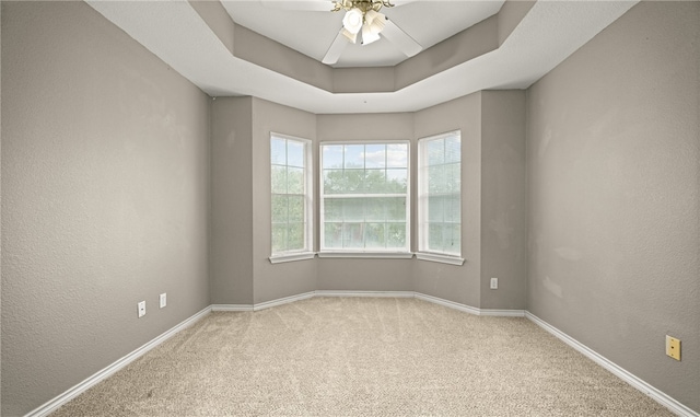 carpeted spare room featuring a raised ceiling and ceiling fan