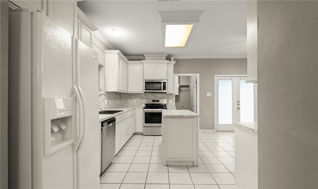 kitchen featuring sink, stainless steel appliances, ornamental molding, white cabinets, and a kitchen island