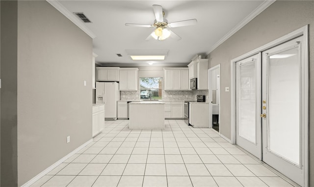 kitchen featuring white cabinets, a center island, stainless steel appliances, crown molding, and french doors