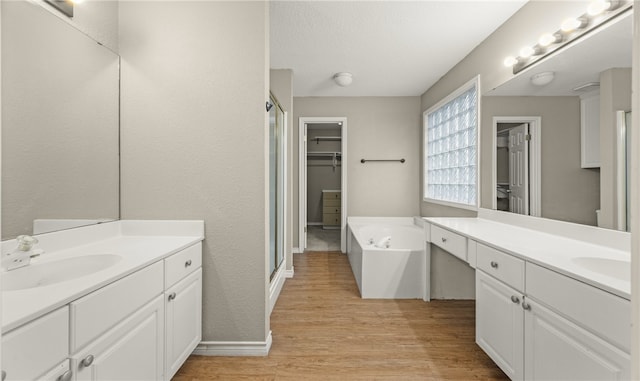 bathroom featuring vanity, hardwood / wood-style floors, a textured ceiling, and plus walk in shower