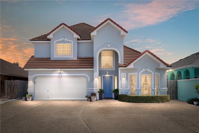 mediterranean / spanish home with driveway, an attached garage, and a tiled roof