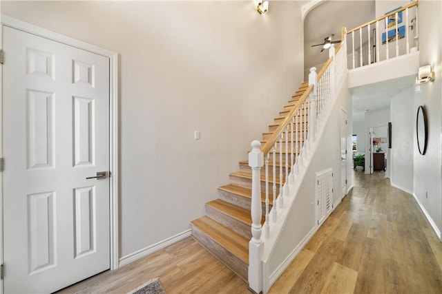 staircase featuring baseboards, ceiling fan, and wood finished floors