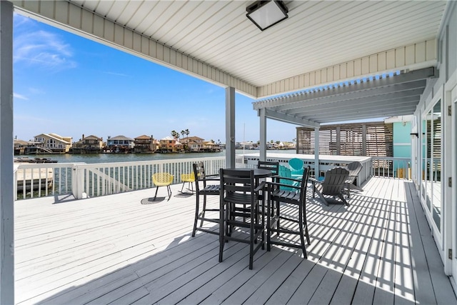 deck featuring a pergola, outdoor dining area, and a water view