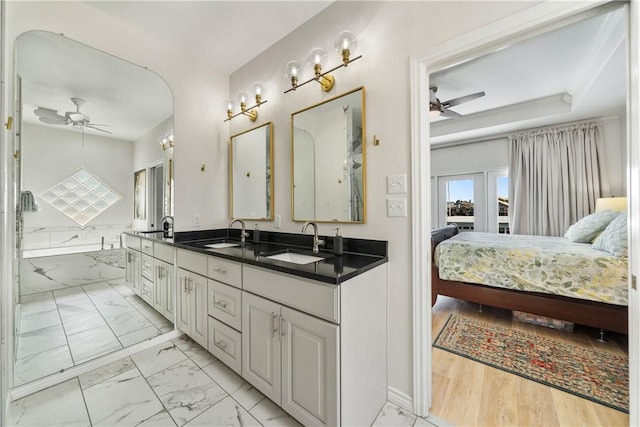 ensuite bathroom featuring marble finish floor, connected bathroom, a sink, and a ceiling fan