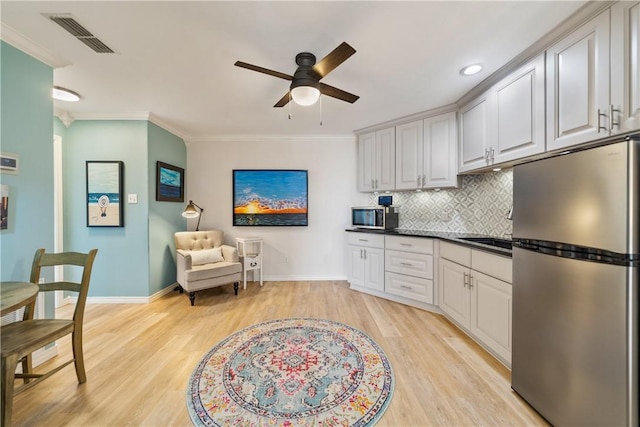 kitchen with backsplash, ceiling fan, light wood-style flooring, visible vents, and appliances with stainless steel finishes