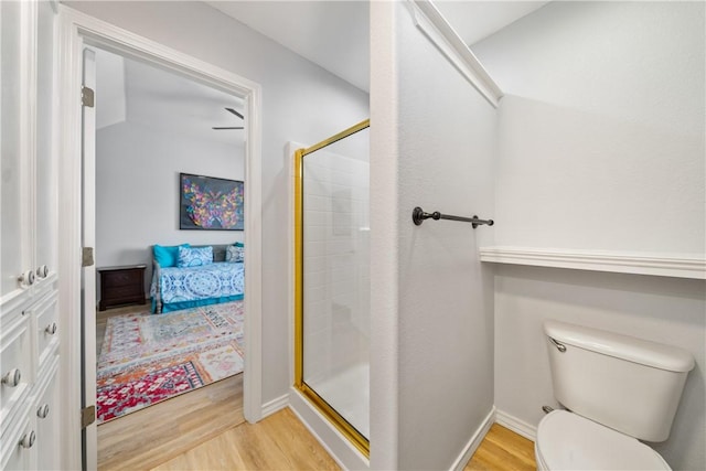 bathroom featuring ensuite bathroom, baseboards, wood finished floors, toilet, and a stall shower