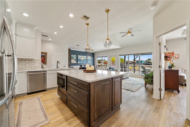 kitchen featuring light countertops, visible vents, stainless steel appliances, white cabinetry, and open floor plan