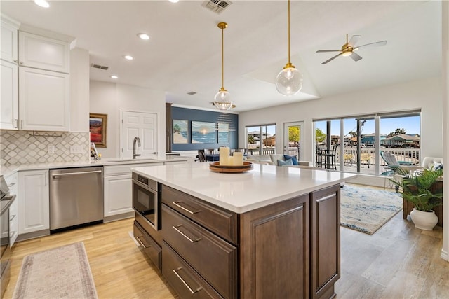 kitchen featuring visible vents, white cabinets, a sink, and stainless steel dishwasher