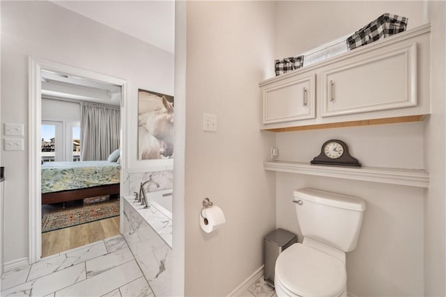 bathroom with baseboards, marble finish floor, connected bathroom, toilet, and a garden tub