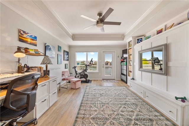 office space with a ceiling fan, a raised ceiling, crown molding, and light wood finished floors