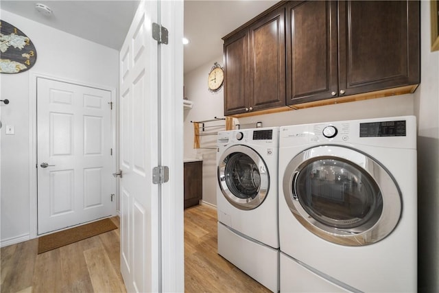 clothes washing area featuring independent washer and dryer, cabinet space, and light wood-style floors
