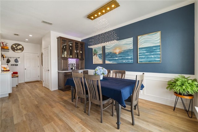 dining area featuring visible vents, light wood-style flooring, and a notable chandelier