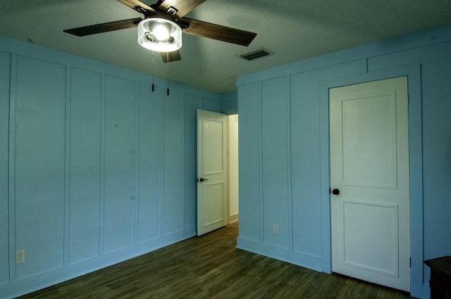 315 W Greenwood Ave, Aransas Pass, TX 78336 - unfurnished bedroom featuring a textured ceiling, a decorative wall, dark wood-style flooring, and visible vents