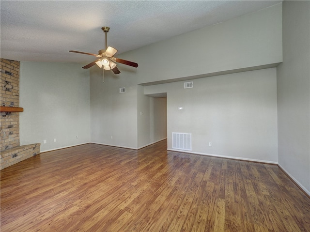 unfurnished living room featuring a fireplace, hardwood / wood-style floors, vaulted ceiling, a textured ceiling, and ceiling fan