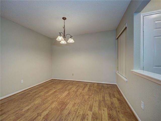 unfurnished room featuring light hardwood / wood-style flooring, a chandelier, and a textured ceiling