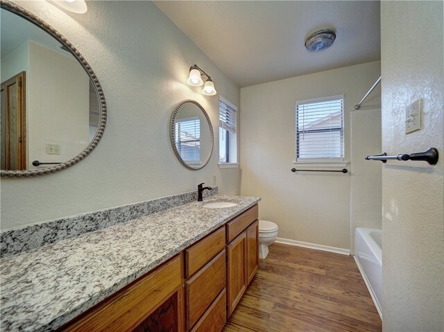 full bathroom with hardwood / wood-style floors, vanity, toilet, and tiled shower / bath combo