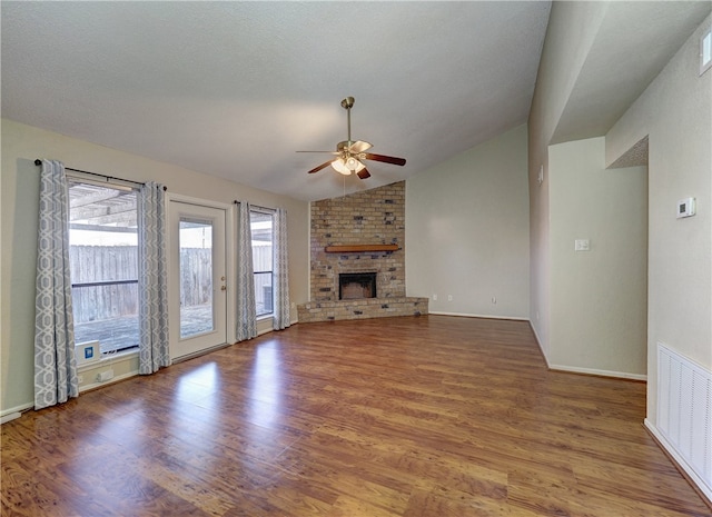 unfurnished living room with ceiling fan, wood-type flooring, a textured ceiling, lofted ceiling, and a fireplace