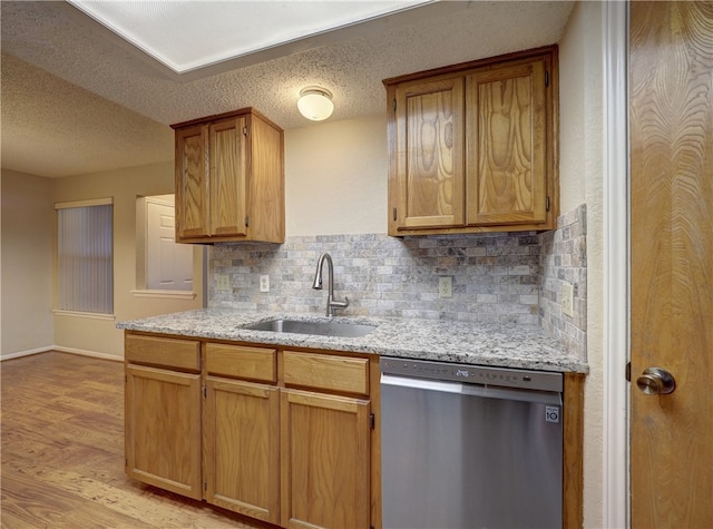 kitchen featuring sink, stainless steel dishwasher, a textured ceiling, light hardwood / wood-style floors, and backsplash