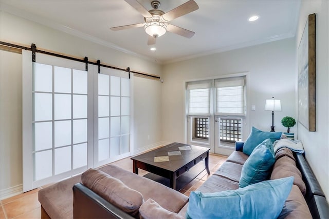 living room featuring ceiling fan, a barn door, ornamental molding, and light tile patterned floors