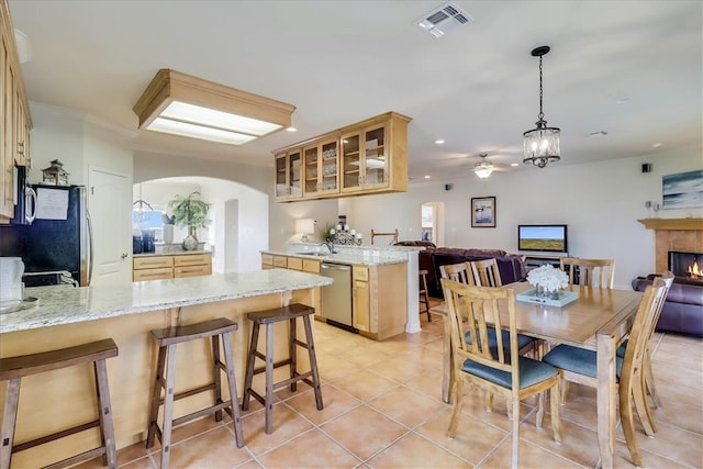 dining space featuring light tile patterned flooring, sink, ornamental molding, and a tiled fireplace