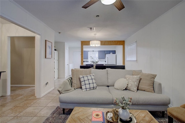 tiled living room with ornamental molding and ceiling fan