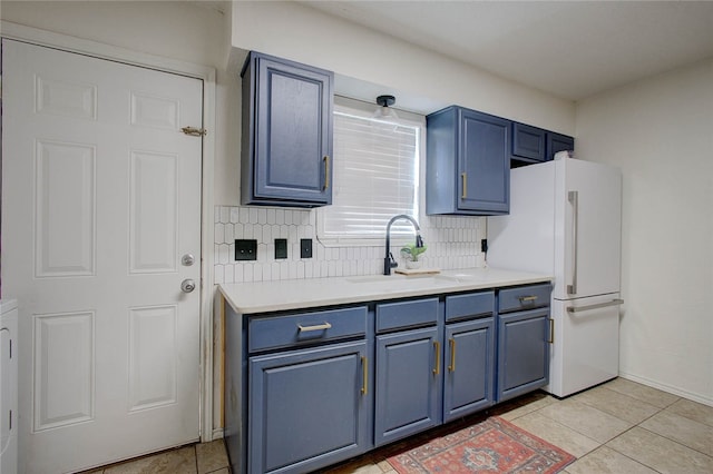 kitchen with light tile patterned flooring, white fridge, decorative backsplash, and blue cabinets