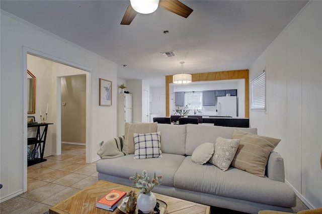 living room featuring ceiling fan, crown molding, and light tile patterned floors