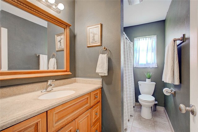 bathroom with toilet, vanity, and tile patterned floors