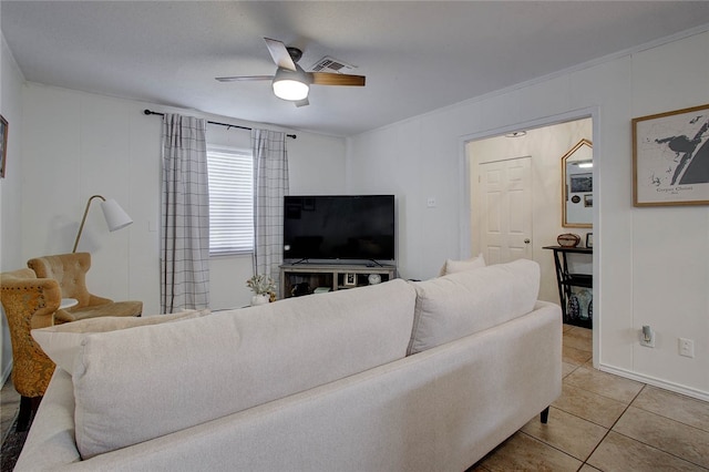 tiled living room with ceiling fan and crown molding