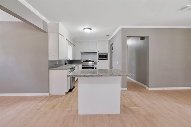 2121 Cedar St, Paris, TX 75460 - kitchen with appliances with stainless steel finishes, crown molding, white cabinetry, light wood-type flooring, and a center island
